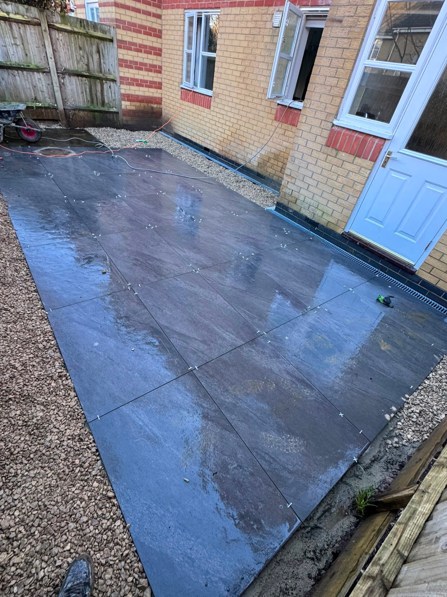 Dark slate-effect porcelain patio in Gloucester with a channel drain along the house wall