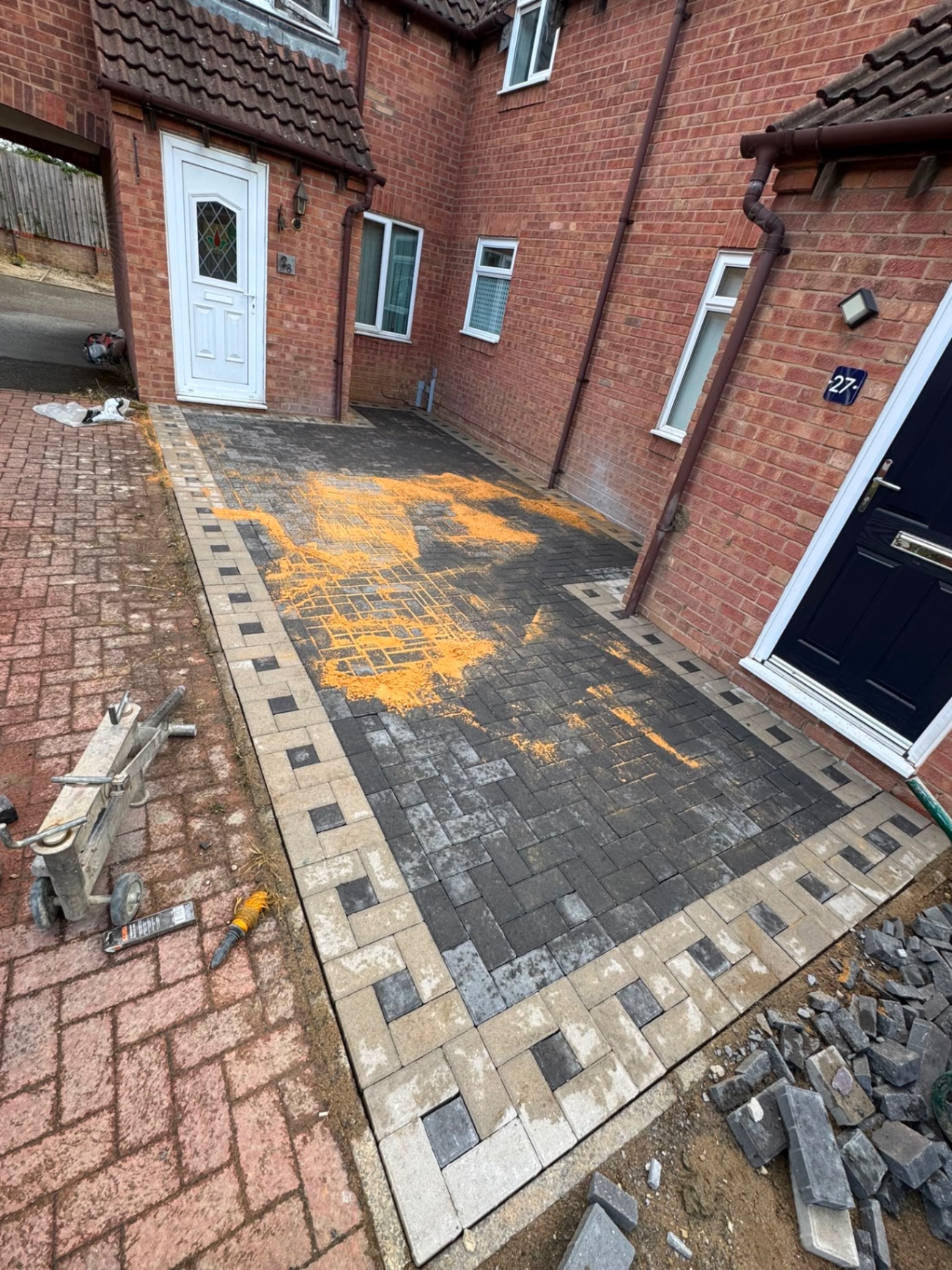 Charcoal block paved side drive in Gloucester with buff border being jointed with kiln-dried sand