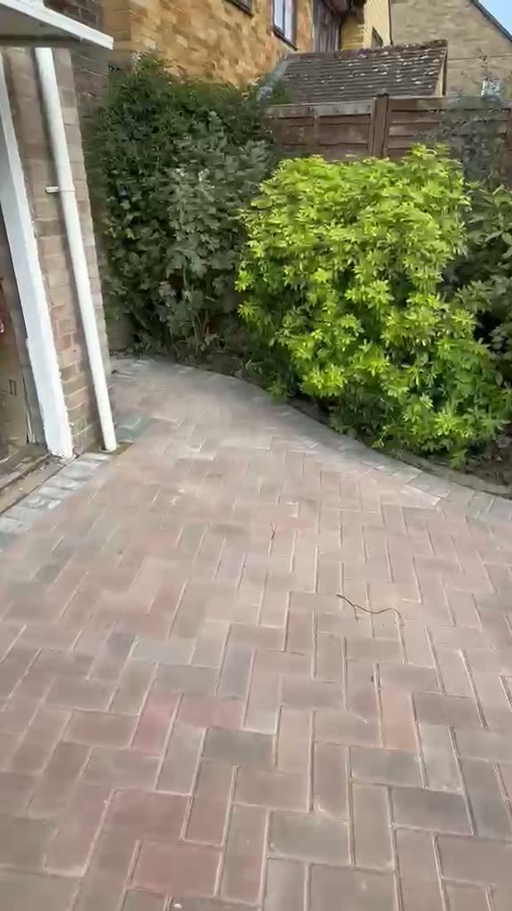 Red brindle herringbone block paving curving around the side of a Gloucester house