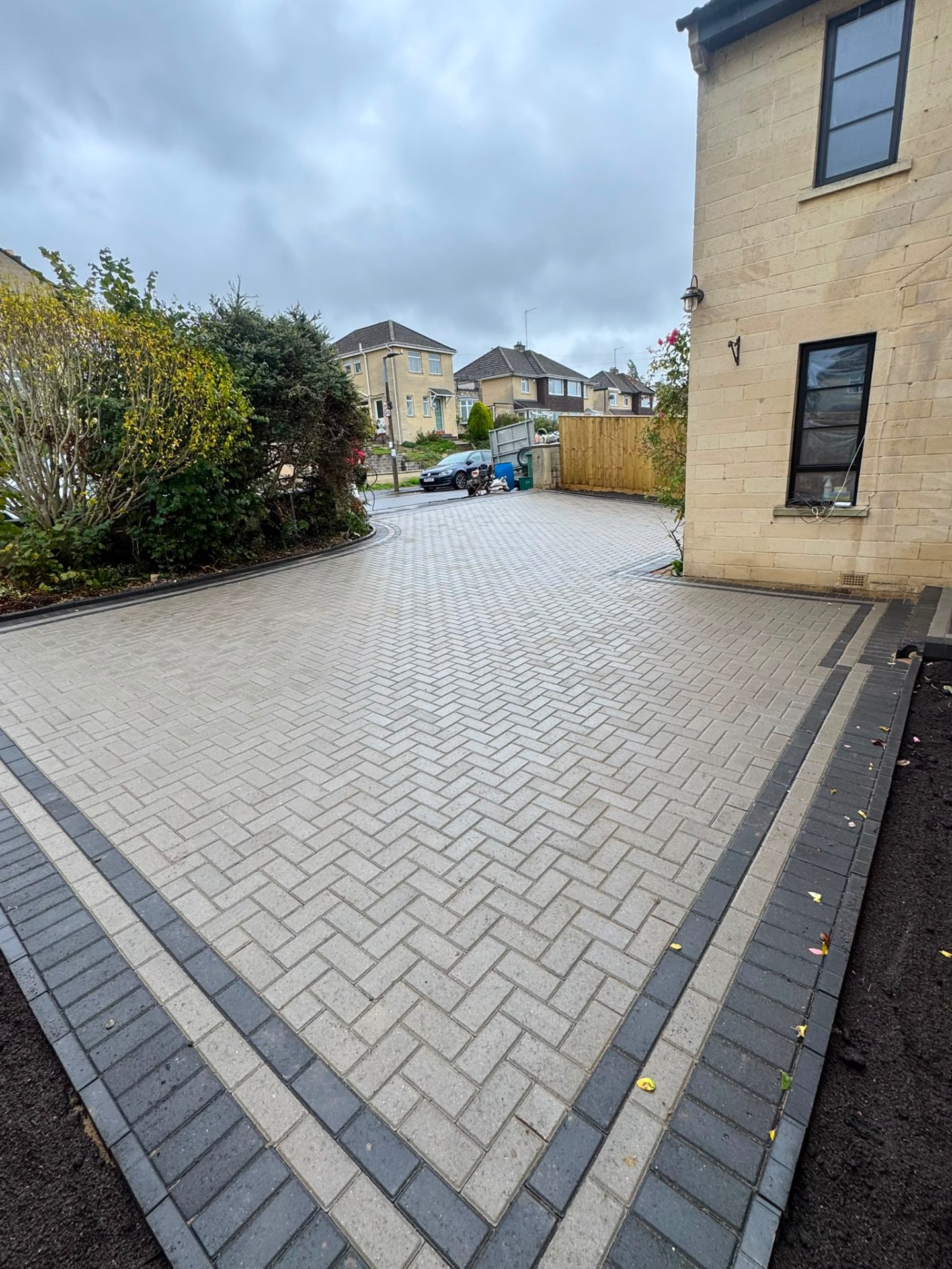 Wide grey block paved driveway and turning area in Gloucester bordered in charcoal blocks