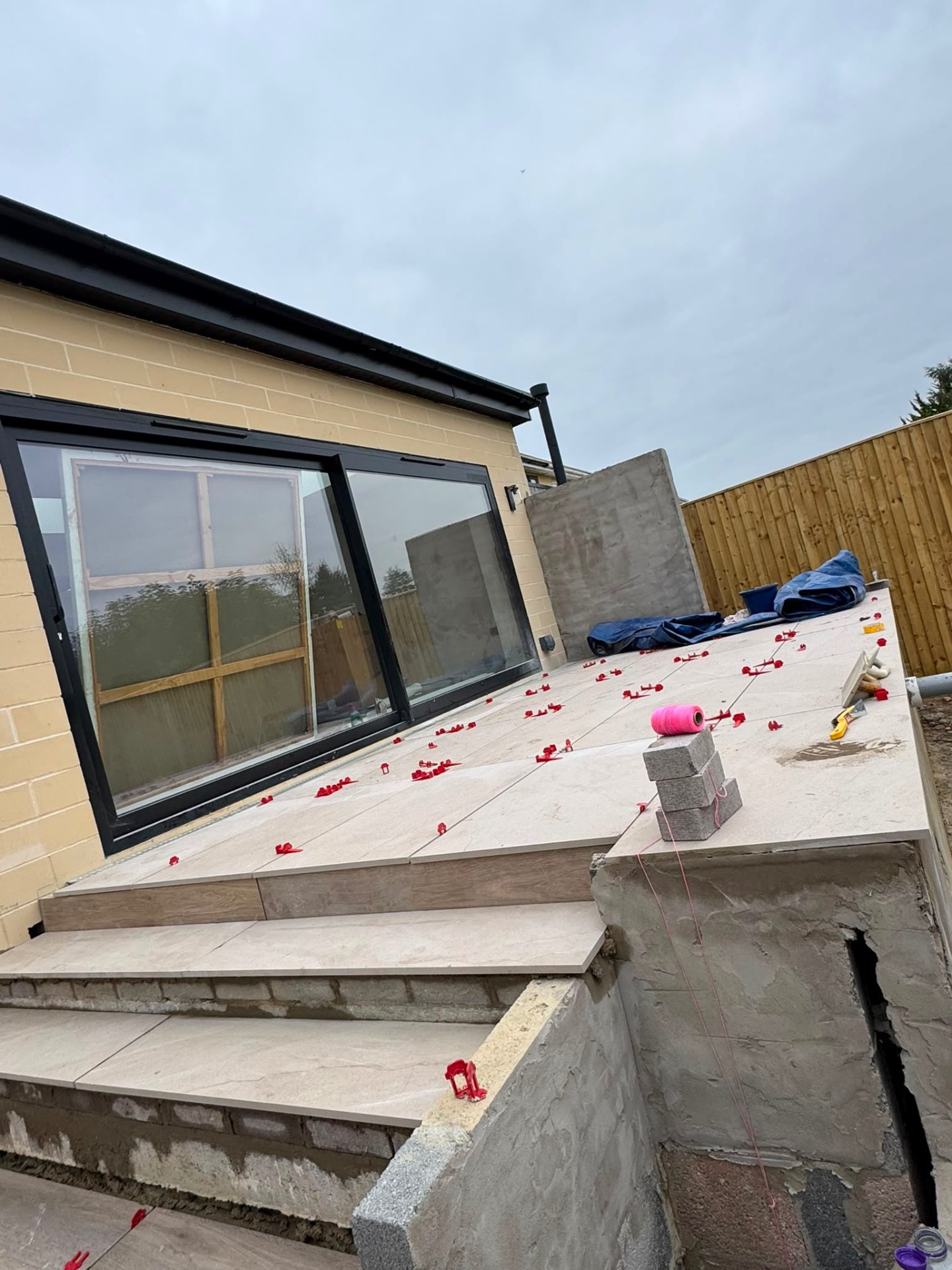 Light porcelain terrace and steps under construction outside bifold doors on a Gloucester new build
