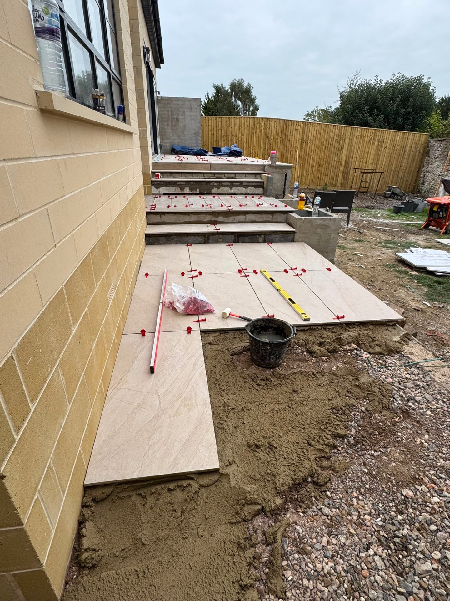 Tiered sandstone-effect porcelain terrace under construction in a Gloucester garden