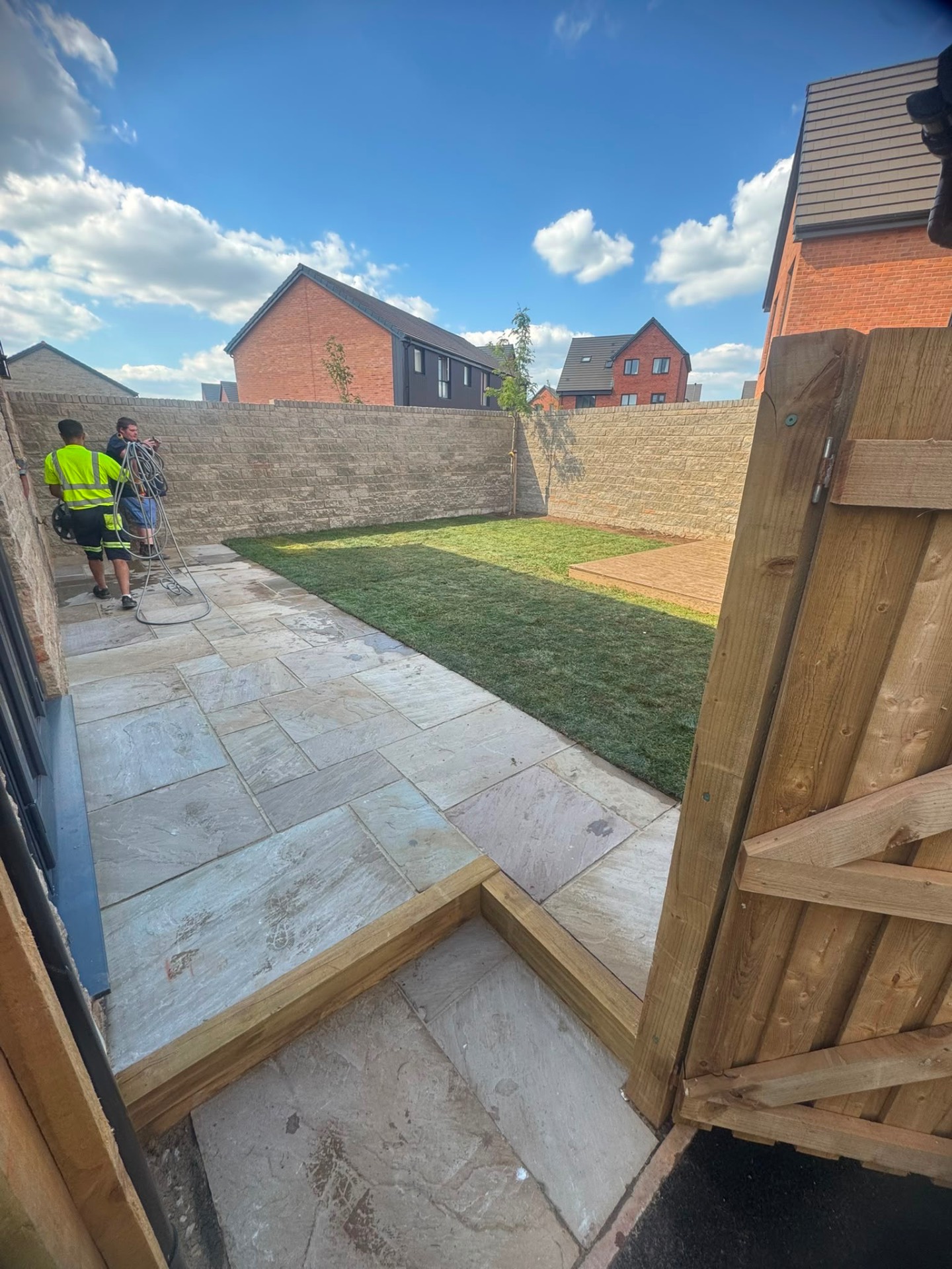 New build rear garden with sandstone patio, fresh turf lawn and raised timber decking in Gloucester