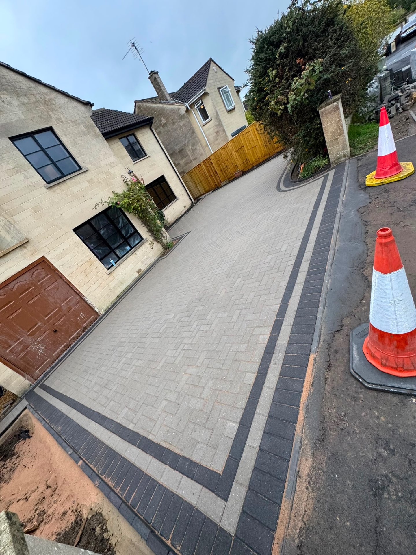 Grey herringbone block paved driveway in Gloucester with a charcoal double border sweeping to the road