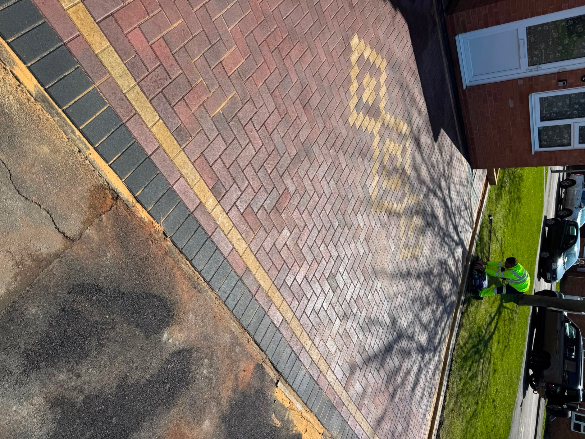 Overhead view of a 45 degree herringbone block paving driveway with buff border and charcoal kerb
