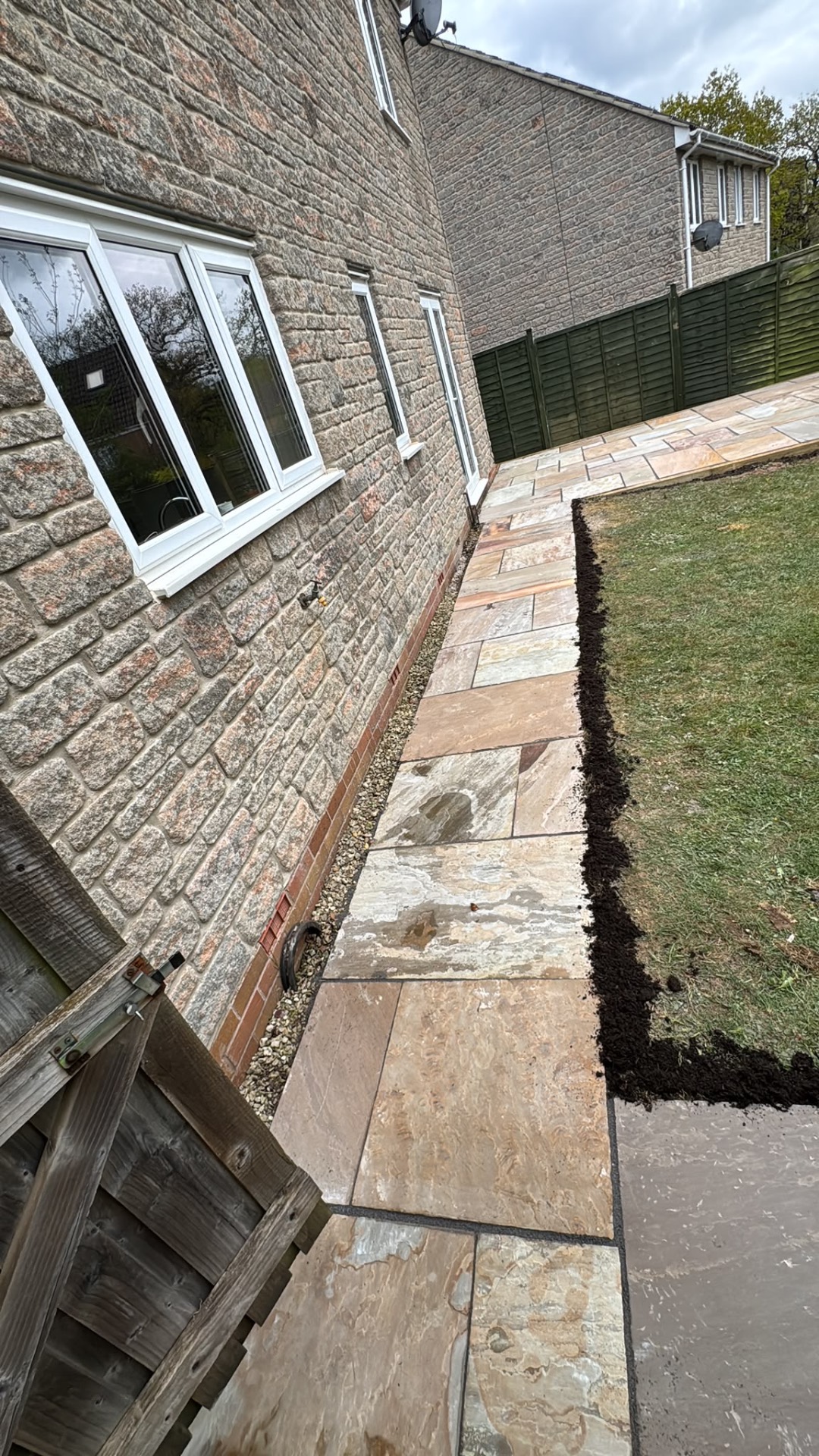Indian sandstone path along the side of a stone house with gravel margin in Gloucester
