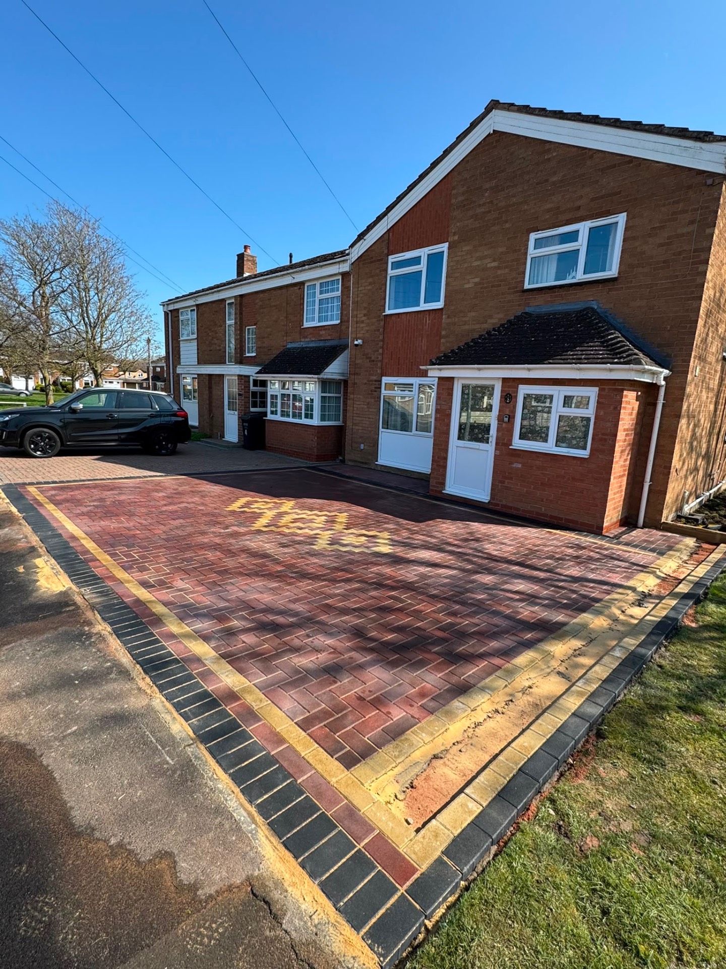 Wide view of a completed red brindle block paving driveway with charcoal kerb in Gloucester