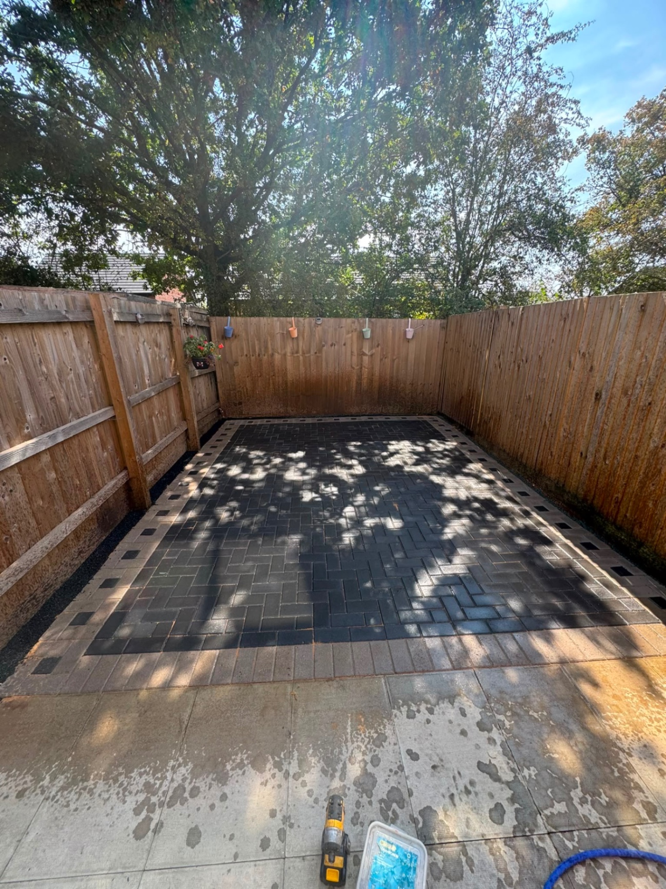 Charcoal block paved rear courtyard with buff border between fence panels in Gloucester