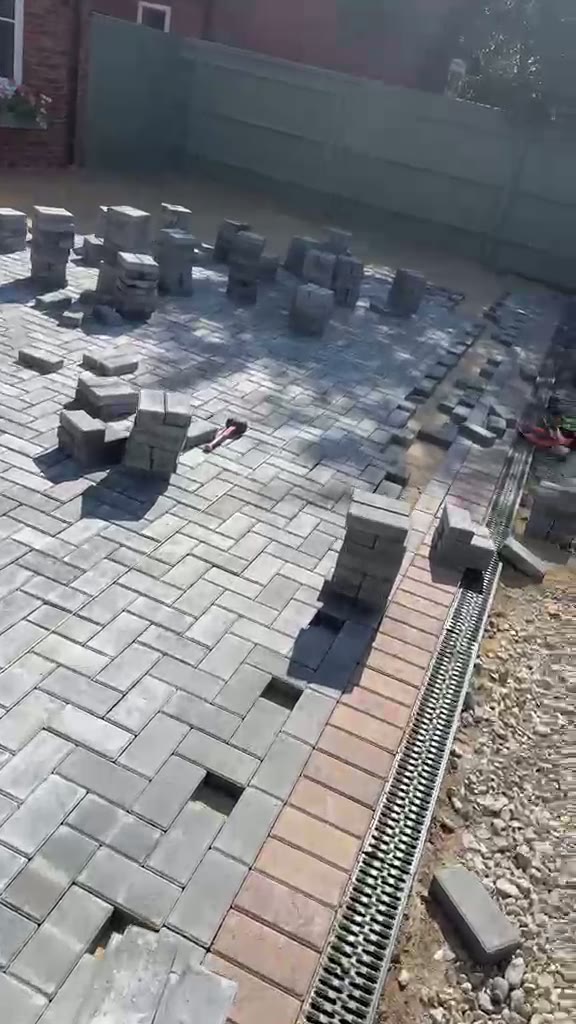 Block paving part-laid across a Gloucester driveway with red soldier edge and linear drainage channel