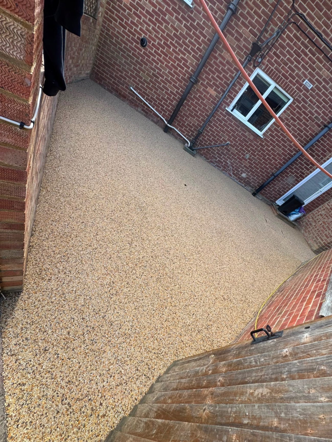 Gold resin bound side return laid between two brick house walls in Gloucester