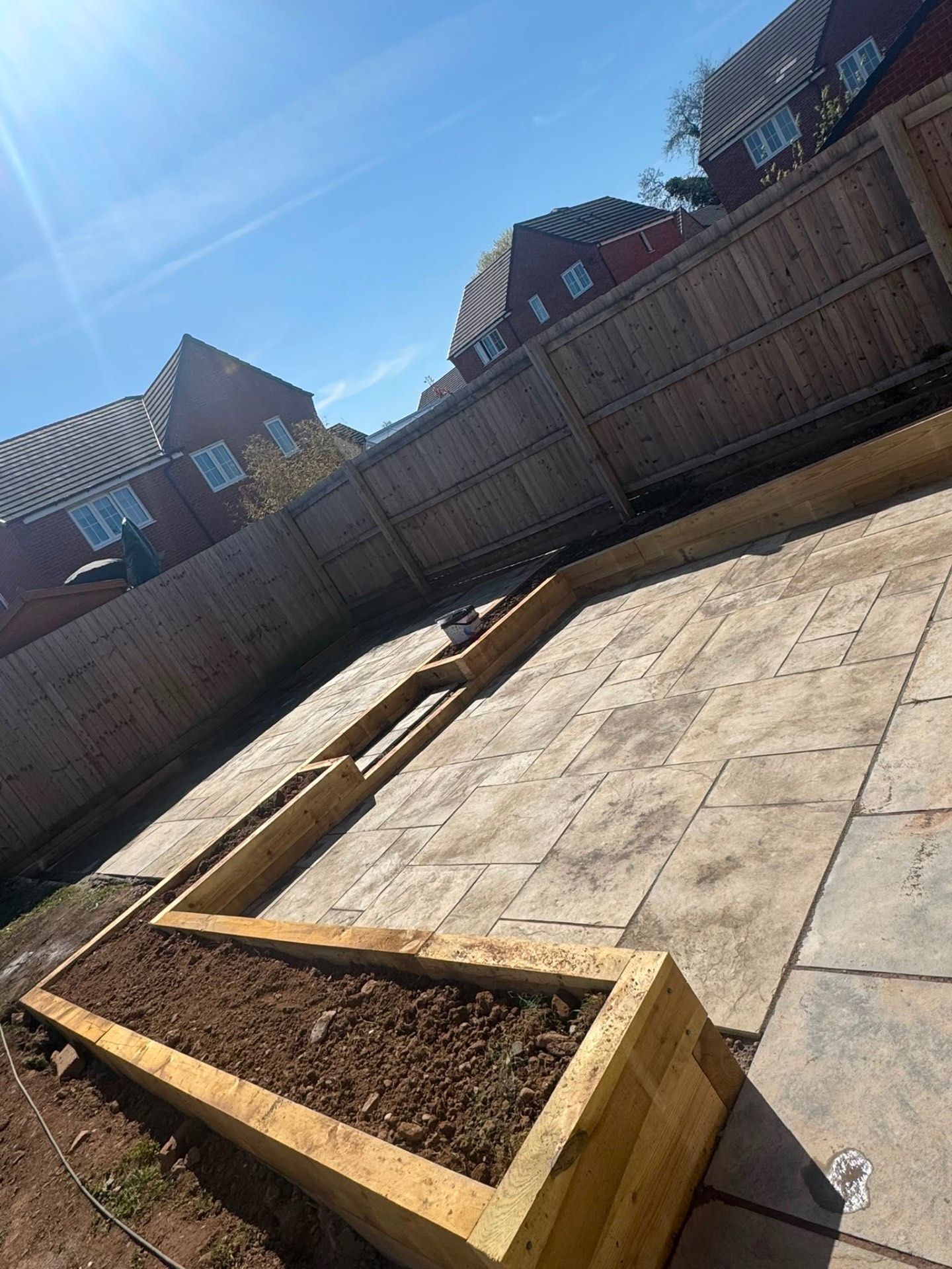 Large-format riven patio with treated sleeper raised beds in a new build garden in Gloucester